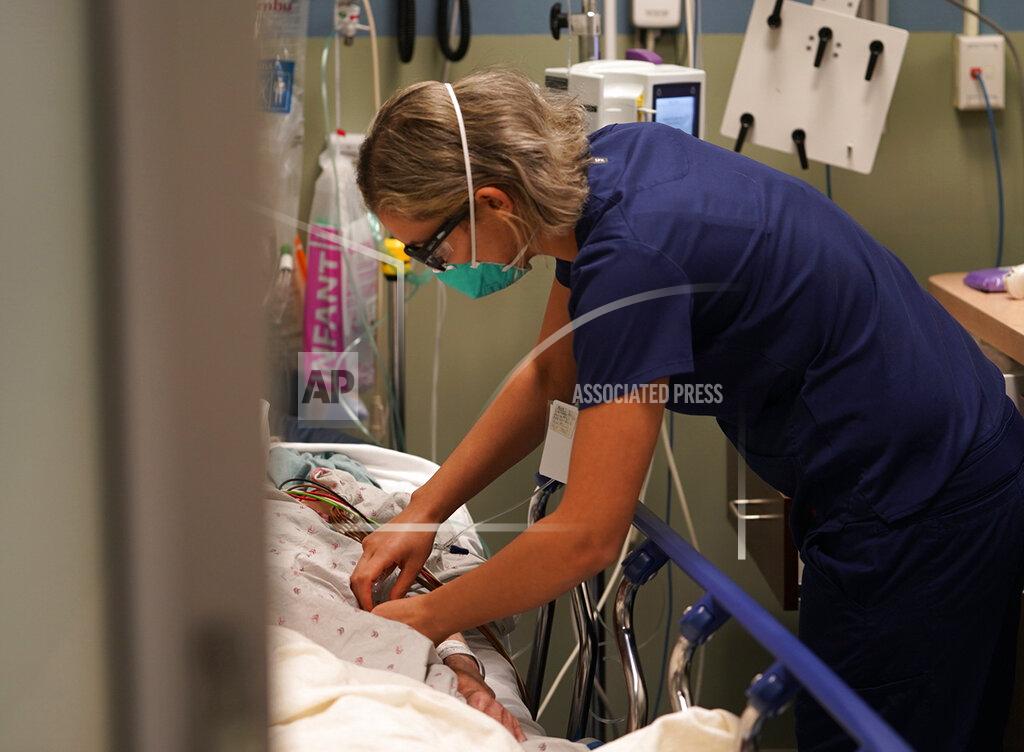 Damian Dovarganes Registered nurse Sandra Younan adjusts an intravenous line for a patient at the emergency room of Providence Cedars-Sinai Tarzana Medical Center in the Tarzana neighborhood of Los Angeles on Thursday, March 11, 2021. Younan spent the last year juggling long hours as she watched many patients struggle with the coronavirus and some die. Then there were the patients who claimed the virus was fake or coughed in her face, ignoring mask rules. One man stormed out of the hospital after a positive COVID-19 test, refusing to believe it was accurate. (AP Photo/Damian Dovarganes)
