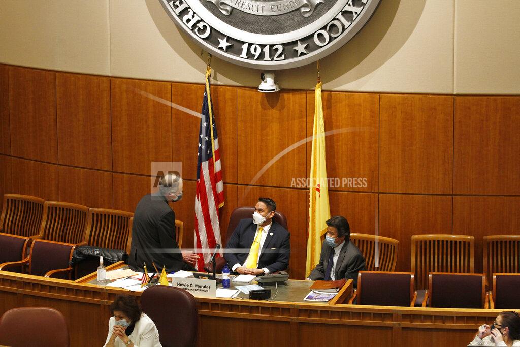Cedar Attanasio State Senate Majority Floor leader Peter Wirth, of Santa Fe, sits on the desk of Lt. Gov. Howie Morales, center, in conversation with with Sen. Pete Campos, of Las Vegas, during a recess of the senate annual legislative session on Friday, March 19, 2021, in Santa Fe, N.M. The late-night recess was called after an acrimonious exchange between two other senators during a debate on a sick leave provision. (AP Photo/Cedar Attanasio)
