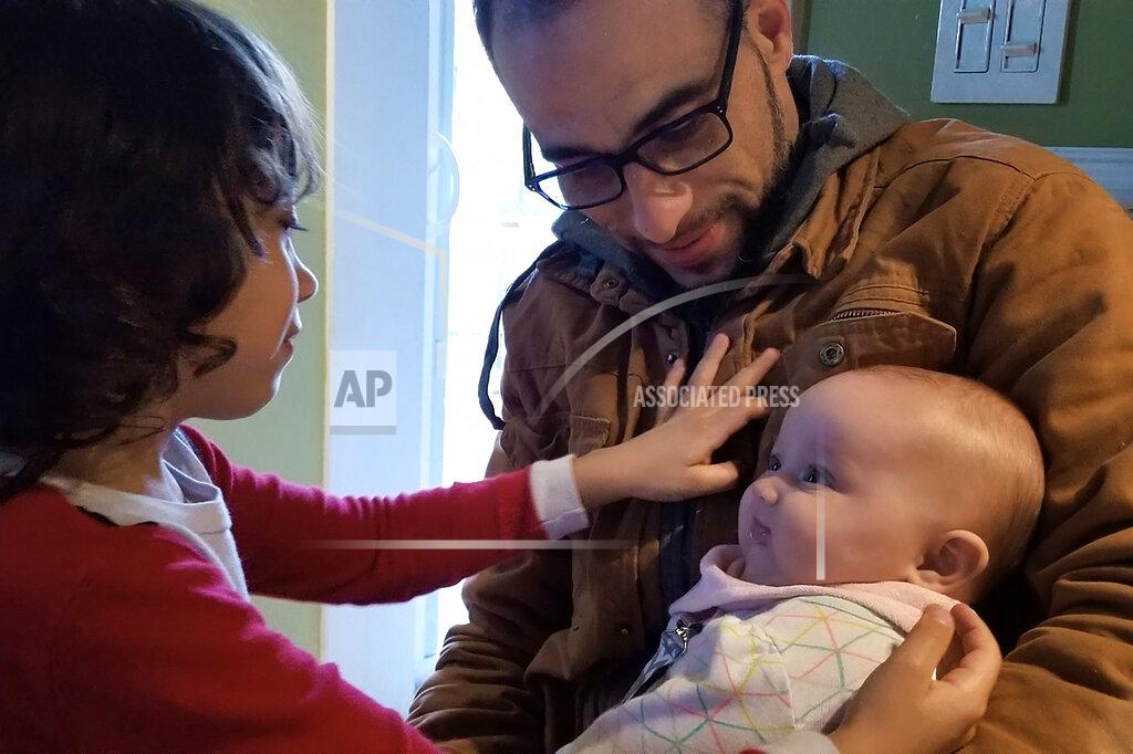 Allison Andrade-Cullen In this March 2019 photo provided by Allison Andrade-Cullen, her husband Flavio Andrade Prado, a Brazilian national, top right, holds their daughter Saoirse Andrade-Cullen, right, as their son Gabriel Andrade-Cullen, left, looks on at their home, in Brockton, Mass., as Andrade Prado prepares to leave for work. Andrade Prado is being held by Immigration and Customs Enforcement, or ICE, at the Plymouth County House of Corrections. The number of detainees nationwide has more than doubled since the end of February, to nearly 27,000, according to recent data from U.S. Immigration and Customs Enforcement. (Allison Andrade-Cullen via AP)