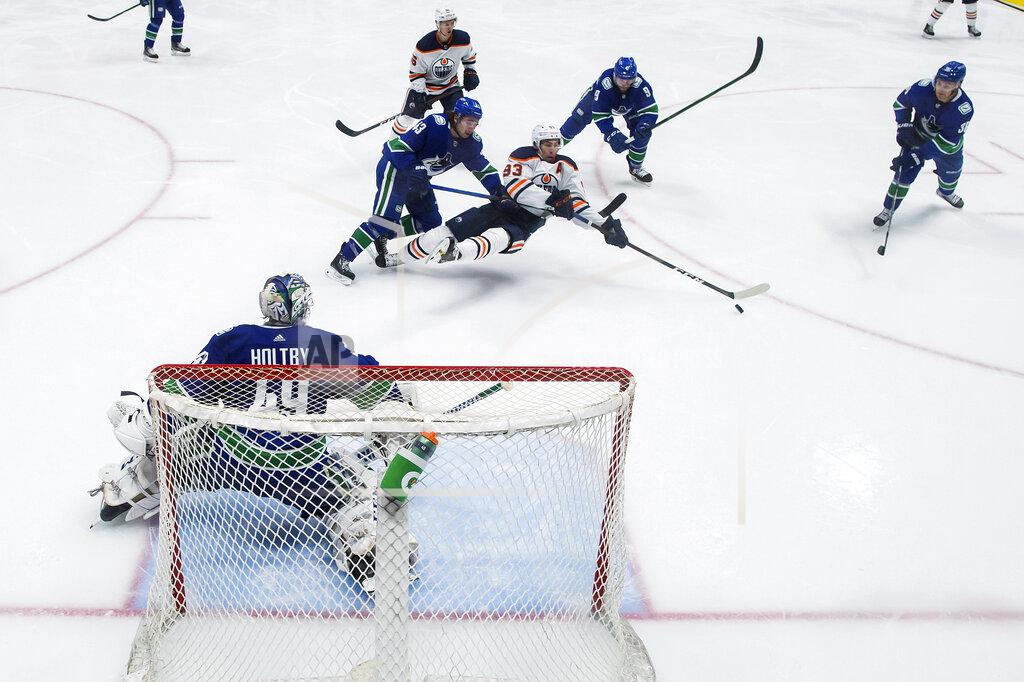 Darryl Dyck Vancouver Canucks' Quinn Hughes (43) hooks Edmonton Oilers' Ryan Nugent-Hopkins (93) to the ice in front of Vancouver goalie Braden Holtby (49) during the second period of an NHL hockey game, Monday, May 3, 2021, in Vancouver, British Columbia. (Darryl Dyck/The Canadian Press via AP)