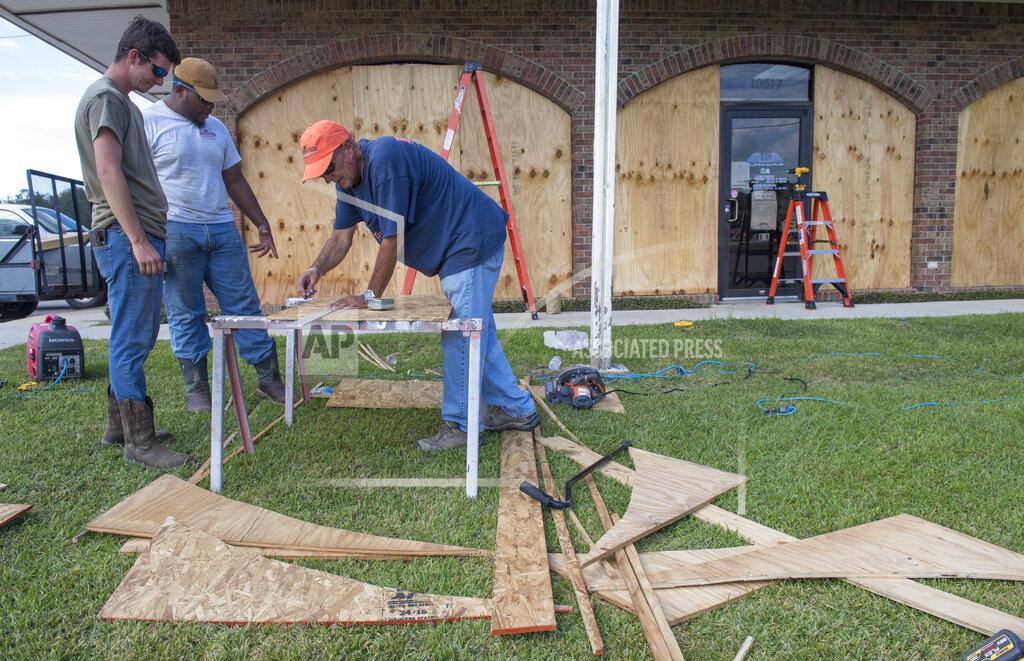 Chris Granger Bernie Arnould, center, gets help from Kaden Ashley and D.J. Hebert, left, all with Pelican Companies, as they board up the windows to the front of MC Bank in Amelia, La., Wednesday, Oct., 7, 2020, in In preparation for Hurricane Delta. (Chris Granger/The Times-Picayune/The New Orleans Advocate via AP)