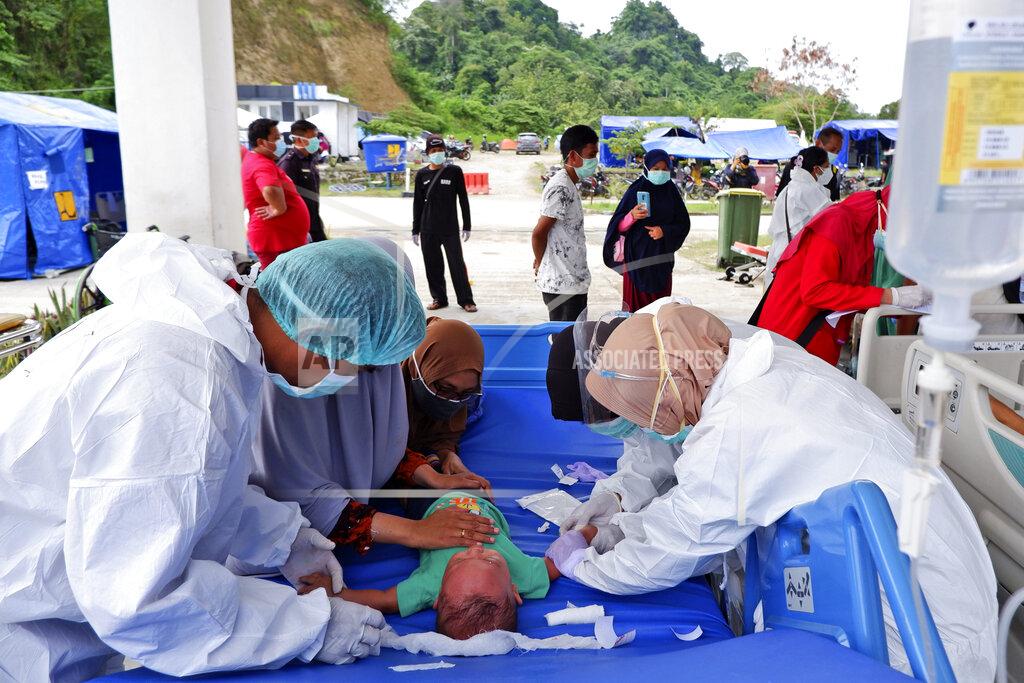 Daeng Mansur A child receives medical treatment at the entrance hallway of a hospital as patients are treated outside amid fears of aftershocks at a hospital affected by an earthquake in Mamuju, West Sulawesi, Indonesia, Sunday, Jan. 17, 2021. Rescuers retrieved more bodies from the rubble of homes and buildings toppled by the magnitude 6.2 earthquake while military engineers managed to reopen ruptured roads to clear access for relief goods. (AP Photo/Daeng Mansur)