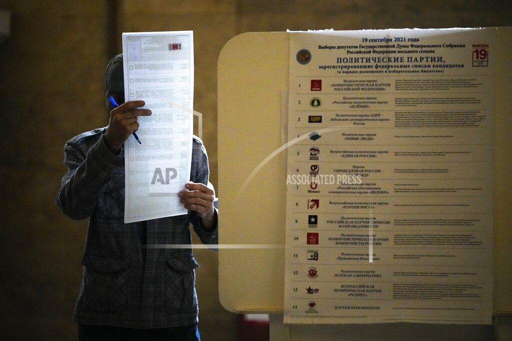 Alexander Zemlianichenko A man reads his ballot at a polling station during the Parliamentary elections in Moscow, Russia, Sunday, Sept. 19, 2021. Russia has begun the third day of voting for a new parliament that is unlikely to change the country's political complexion. There's no expectation that United Russia, the party devoted to President Vladimir Putin, will lose its dominance in the State Duma. (AP Photo/Alexander Zemlianichenko)