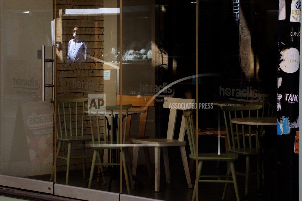 Petros Karadjias A man wearing a face mask is reflected in a window of a closed restaurant in central capital Nicosia, Cyprus, Friday, March 12, 2021. Cyprus put the breaks on a wider loosening of COVID-19 restrictions by keeping middle school students at home for two more weeks as the infection rate remains high partly because of how widespread the U.K. variant has become. (AP Photo/Petros Karadjias)