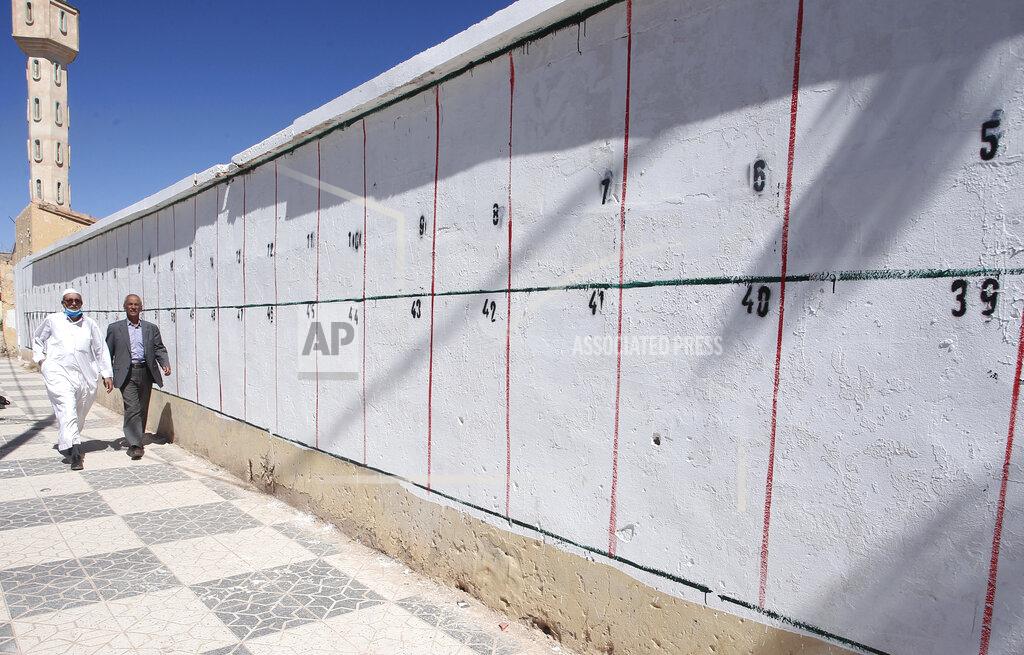 Fateh Guidoum Men walk by a wall where electoral posters for the upcoming parliamentary elections will be placed, Thursday, May 20, 2021 in Ain Ouessara, 200 kilometres (125 miles) south of Algiers. Initially planned for April 22, the the legislative election will take place on June 12, 2021 in the North African country. (AP Photo/Fateh Guidoum)