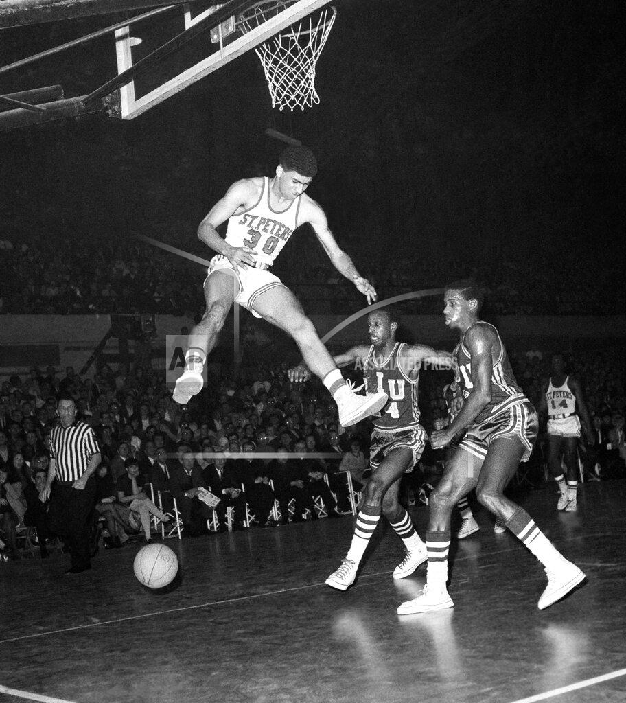 Marty Lederhandler FILE - Elnardo Webster (10) of St. Peter's College leaps high for rebound off his basket, but lost right of the ball while he was in mid-air, during the first period of National Invitation Tournament college basketball game against Long Island University at the Armory in Jersey City, N.J., on Feb. 28, 1968. Webster, who put Saint Peter's basketball on the map more than a half century ago in leading the Peacocks to the NIT semifinals in 1968, died on Tuesday, March 21, 2022, in Morristown, N.J., after being hospitalized with a heart issue, former teammates said. He was 74. (AP Photo/Marty Lederhandler, File)