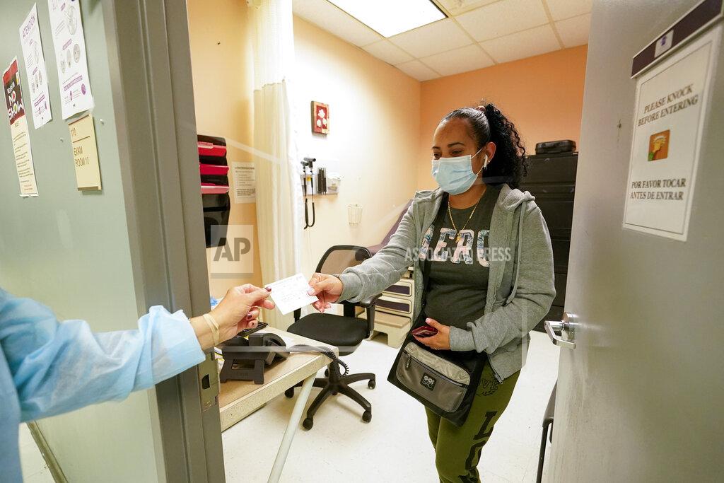 Registered nurse Anna Yadgaro, left, hands Geidy Chirinos her vaccination card after inoculating her with the second dose of the Moderna COVID-19 vaccine, Wednesday, May 12, 2021, at the Joseph P. Addabbo Family Health Center in the Far Rockaway neighborhood of the Queens borough of New York. (AP Photo/Mary Altaffer)