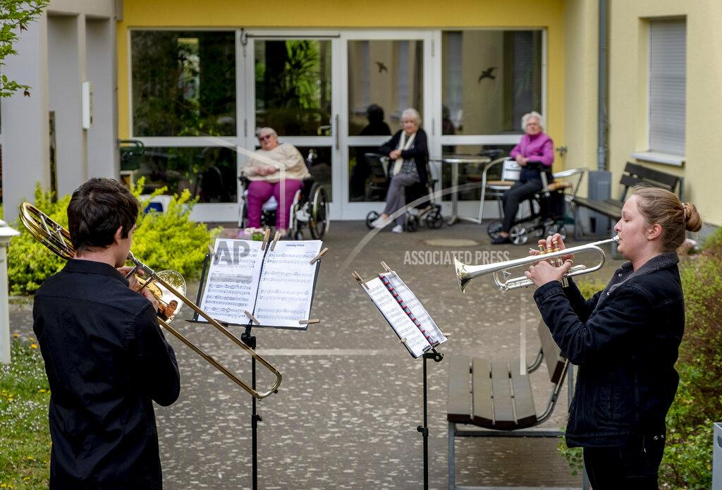 Michael Probst FILE - In this April 13, 2020 file photo, young musicians plays the trumpet, right, and trombone in the garden of a retirement and nursing home in Karben near Frankfurt, Germany. They played various pieces for the old people who are due to the coronavirus not allowed to leave the building. More than 50,000 people have died after contracting COVID-19 in Germany, a number that has risen swiftly over recent weeks as the country has struggled to bring down infection figures. (AP Photo/Michael Probst, File)