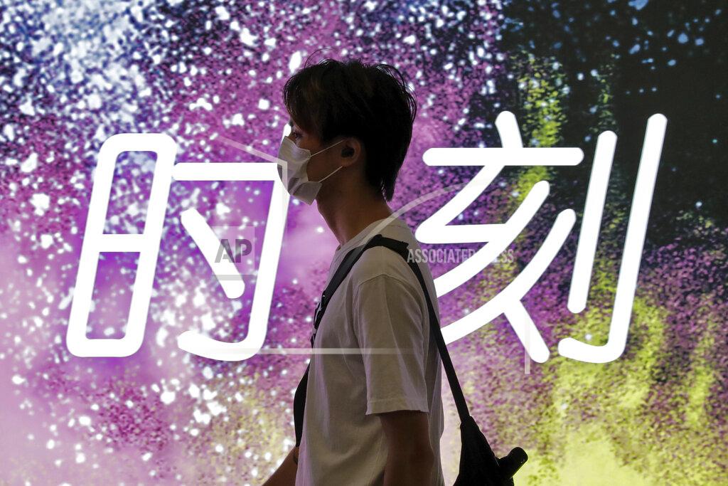Andy Wong A man wearing a face mask to protect against the new coronavirus walks by an advertising board displaying the words "Time" at a subway station in Beijing, Wednesday, July 29, 2020. China reported more than 100 new cases of COVID-19 on Wednesday as the country continues to battle an outbreak in Xinjiang. (AP Photo/Andy Wong)