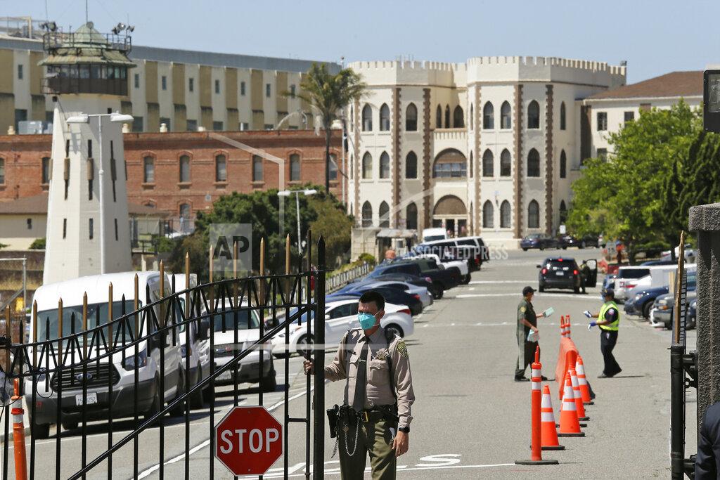 Eric Risberg FILE - In this July 9, 2020, file photo, a correctional officer closes the main gate at San Quentin State Prison in San Quentin, Calif. The family of a 61-year-old California inmate who died of the coronavirus sued state corrections officials Tuesday, March 16, 2021, blaming a botched transfer of infected inmates to San Quentin State Prison that killed 28 inmates and a correctional officer in 2020. (AP Photo/Eric Risberg, File)