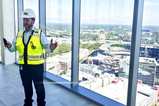Kevin Lavallee, CEO of TK Elevators' North American operations, stands at the top of the company's new elevator testing facility, Wednesday, Oct. 13, 2021, that towers over the Atlanta Braves stadium and surrounding skyscrapers northwest of Atlanta. The 420-foot-tall tower is set to become fully operational early next year. (AP Photo/Jeff Martin)