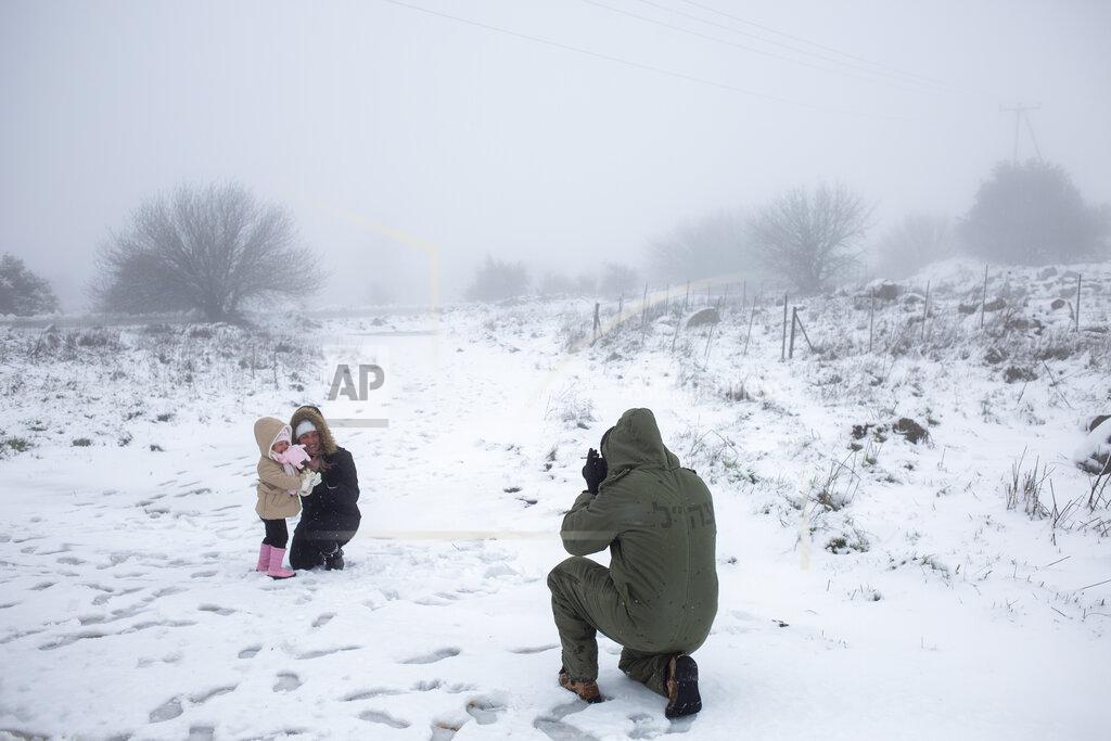 Ariel Schalit An Israeli reserve solider takes photos of his family in the snow near the Quneitra border crossing between Syria and the Israeli-controlled Golan Heights, Wednesday, Feb. 17, 2021. (AP Photo/Ariel Schalit)