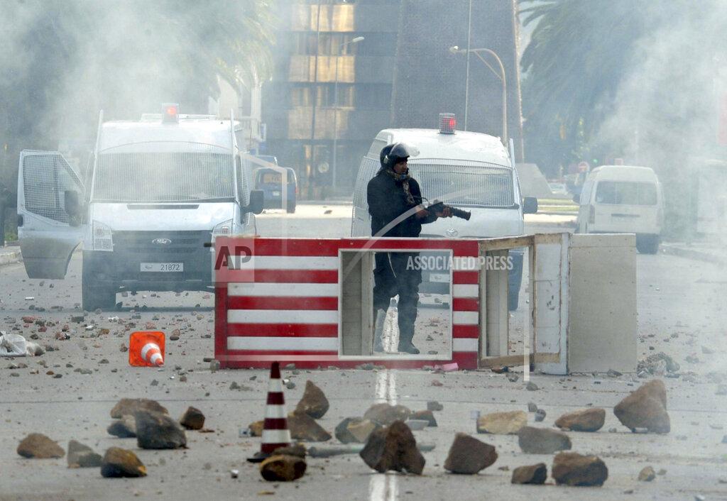 Hedi Ben Salem FILE - In this file photo dated Friday Jan. 14, 2011, a Tunisian riot police officer holds his weapon during riots in Tunis, Friday, Jan. 14, 2011. Tunisia's president declared a state of emergency and announced that he would fire his government as violent protests escalated Friday, with gunfire echoing in the North African country's usually calm capital and police lobbing tear gas at protesters. On Thursday Jan. 14, 2021, Tunisia commemorates 10 years since the flight into exile of its iron-fisted leader, Zine El Abidine Ben Ali, pushed from power in a popular revolt that foreshadowed the so-called Arab Spring. (AP Photo/Hedi Ben Salem)