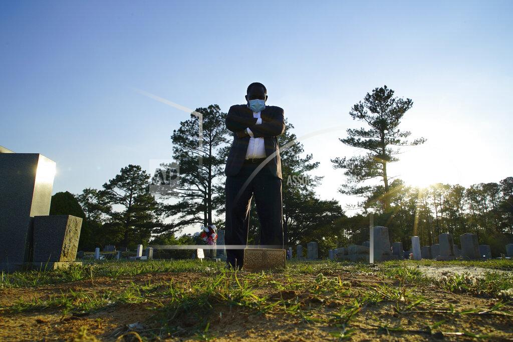 Allen G. Breed Mortician Shawn Troy stands at the grave of his father, William Penn Troy Sr., at Hillcrest Cemetery outside Mullins, S.C., on Sunday, May 23, 2021. The elder Troy, who developed the cemetery, died of COVID-19 in August 2020, one of many Black funeral directors to succumb during the pandemic. “I don’t think I’ll ever get over it,” he said. “But I’ll get through it.” (AP Photo/Allen G. Breed)