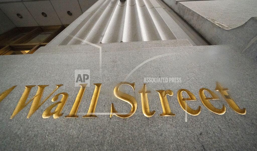FILE - In this Nov. 5, 2020 file photo, a sign for Wall Street is carved in the side of a building. Banks and energy stocks are leading major U.S. indexes mostly lower in the early going on Wall Street, while gains for some Big Tech companies like Microsoft nudged the Nasdaq slightly higher. (AP Photo/Mark Lennihan, File)