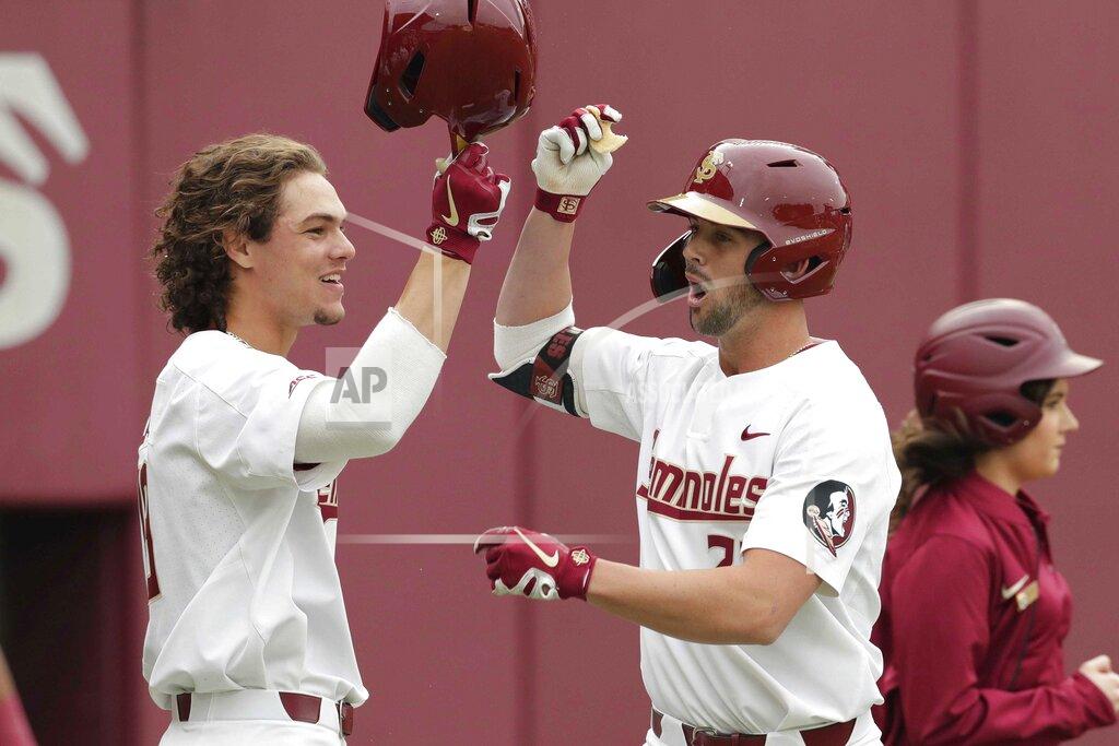 Alicia Devine Florida State NCAA college baseball player Reese Albert, right, takes a bite of a cookie as he fist bumps teammate Elijah Cabell after Albert hit a home run against the Univ. of Maine, Friday Feb. 15, 2019, in Tallahassee, Fla. If all had gone as he hoped, Elijah Cabell and his Florida State teammates would be playing for the College World Series championship this week. Instead, Cabell treks to a ball field in his neighborhood in Winter Park, Florida, most days to work on his game in solitude. (Alicia Devine/Tallahassee Democrat via AP)