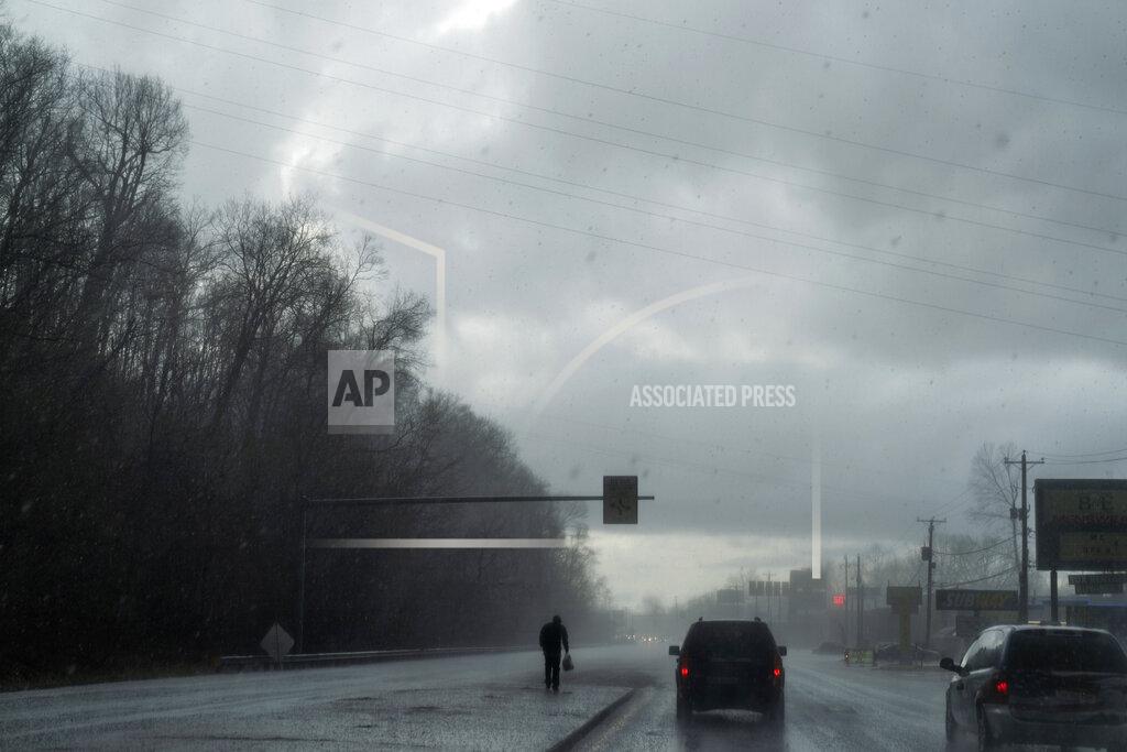 David Goldman A man walks through a hail storm as the Quick Response Team's vehicle drives to visit another client who recently overdosed, Thursday, March 18, 2021, in Huntington, W.Va. Huntington was once ground-zero for this epidemic. Several years ago, they formed the team that within days visits everyone who overdoses to try to pull them back from the brink. It was a hard-fought battle, but it worked. The county's overdose rate plummeted. They wrestled down an HIV cluster. They finally felt hope. Then the pandemic arrived and it undid much of their effort: overdoses shot up again, so did HIV diagnoses. (AP Photo/David Goldman)