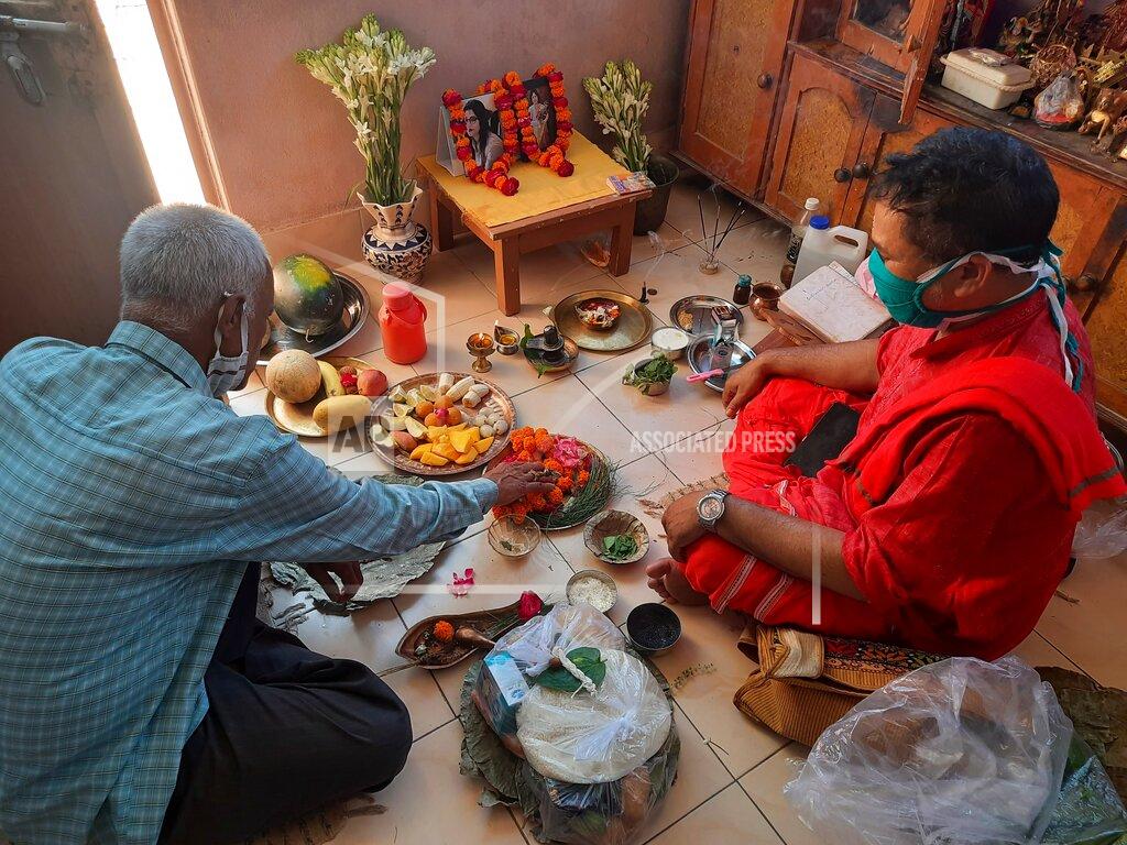 Biswajeet Banerjee Radha Gobindo Pramanik, left, performs a Hindu ritual for his wife and daughter who died of COVID-19 at his home in Lucknow, India, May 23, 2021. “Everyone whom I loved the most has left me,” the 71-year-old said on a recent night as a Hindu priest chanted mantras and performed a ritual for the dead at his home in the northern city of Lucknow. “I am left alone in this world now.” (AP Photo/Rajesh Kumar Singh)