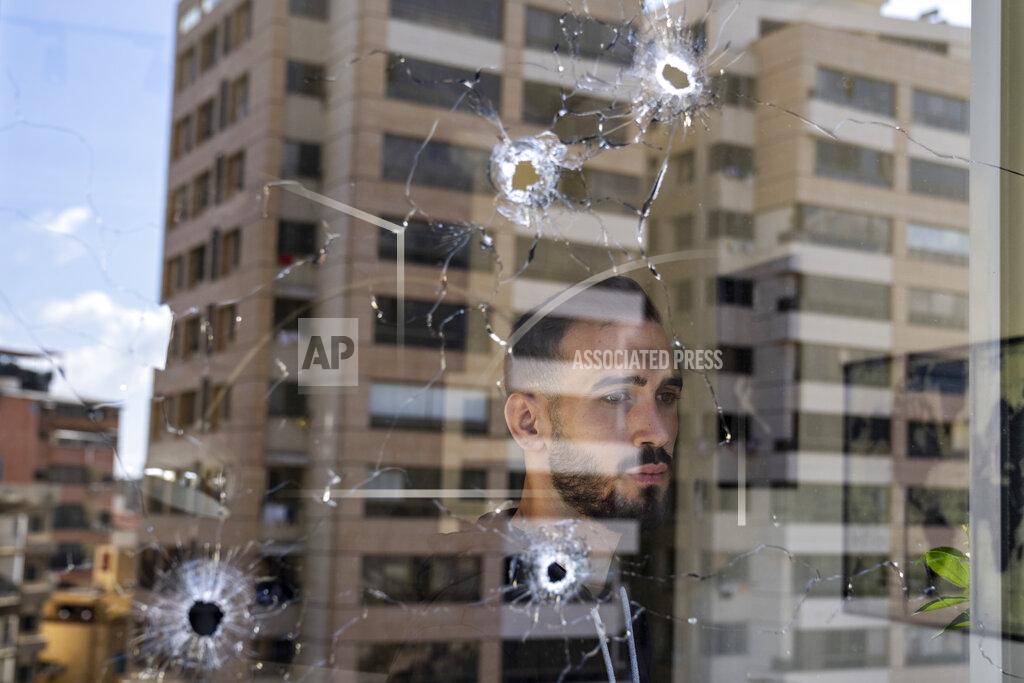 Hassan Ammar An employee looks through an office window riddled with bullet holes after the deadly clashes that erupted last Thursday along a former 1975-90 civil war front-line between Muslim Shiite and Christian areas, in Ain el-Rumaneh neighborhood, Beirut, Lebanon, Tuesday, Oct. 19, 2021. The shootout on the streets of Beirut between rival Christian and Muslim groups has revived memories of the country's 1975-90 civil war and fired up sectarian passions in a country that never dealt with the causes of its violent past. (AP Photo/Hassan Ammar)