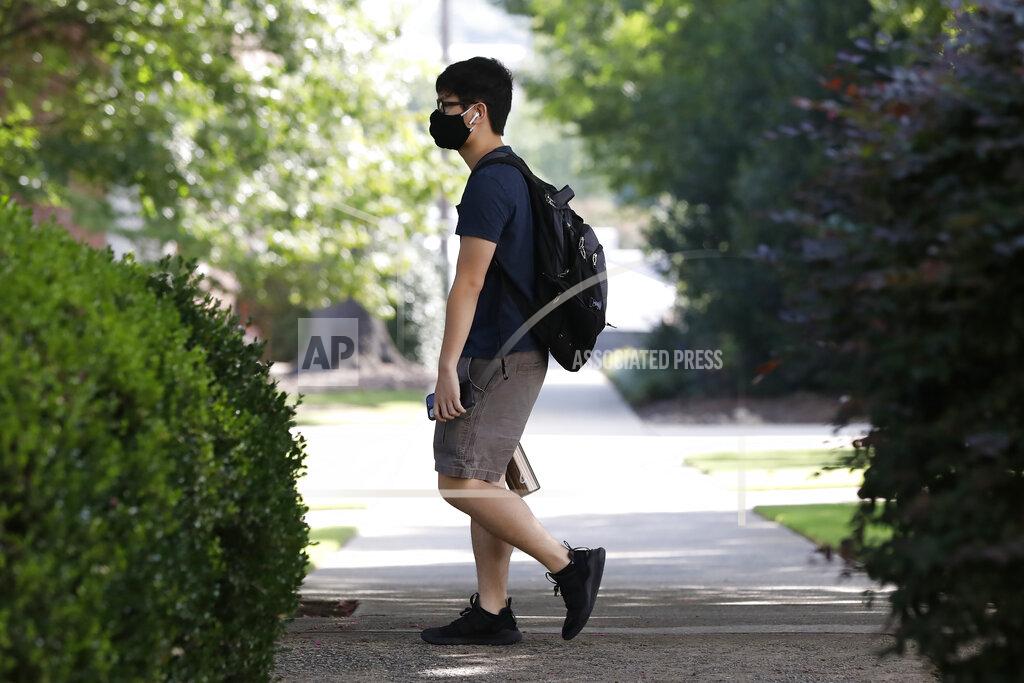 Joshua L. Jones A student, wearing a mask, walks on campus at the University of Georgia, Thursday, Aug. 20, 2020. in Athens, Ga. (Joshua L. Jones/Athens Banner-Herald via AP)