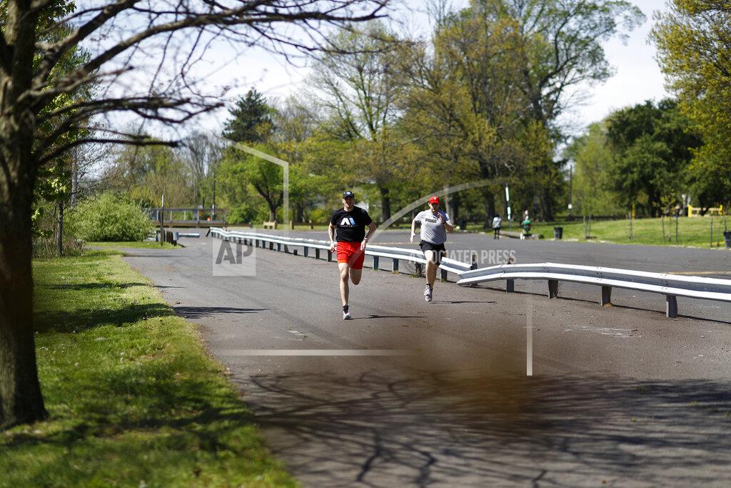 Fighter Kyle Daukaus, left, sprints with his brother and training partner, Chris Daukaus, through Pleasant Hill Park near their home, Saturday, May 2, 2020, in Philadelphia. Kyle, a rising star in the regional MMA promotion Cage Fury Fighting Championships, is still chasing his dream of getting the call to fight for UFC despite the coronavirus pandemic. (AP Photo/Matt Slocum)