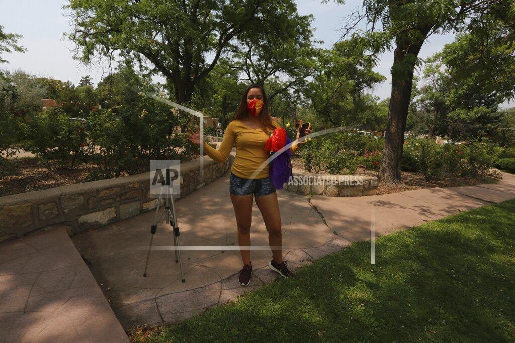 Cedar Attanasio Tina Arons, 32, speaks as she removed her phone from a tripod at the Harvey Cornell Rose Park Monday, Aug. 24, 2020, in Santa Fe, New Mexico. Arons used the video recording setup to capture a dance routine with silk fan veils, draped over her shoulder, for and online she teaches. (AP Photo/Cedar Attanasio)