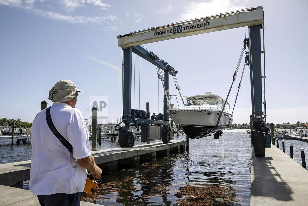 Damon Higgins Brett Hand controls a Marine Travelift with a hand held remote to lift boats out of the water and move them onto the grounds of Palm Beach, Fla., Yacht Center for safe keeping as Hurricane Isaias approaches the Florida coast Saturday, Aug. 1, 2020. Isaias snapped trees and knocked out power as it blew through the Bahamas on Saturday and churned toward the Florida coast, where it is threatening to complicate efforts to contain the coronavirus in a hot spot. (Damon Higgins/The Palm Beach Post via AP)