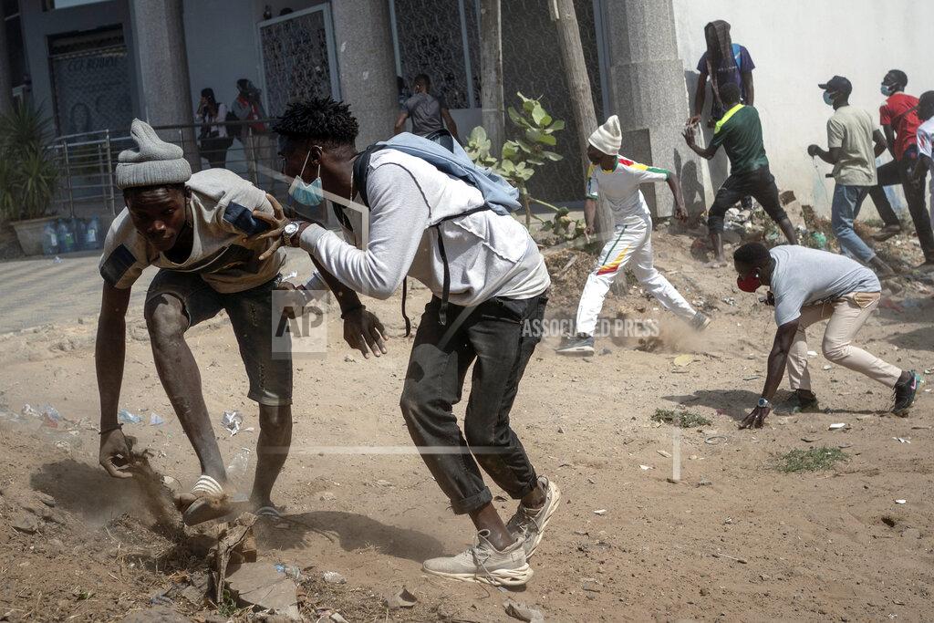 Leo Correa FILE - In this Wednesday, March 3, 2021 file photo, demonstrators take cover during clashes with riot police at a protest in support of main opposition leader and former presidential candidate Ousmane Sonko in Dakar, Senegal. Deadly protests have erupted over the past week in the West African nation of Senegal, long considered a bastion of democracy and a regional leader on diplomacy issues. (AP Photo/Leo Correa, File)