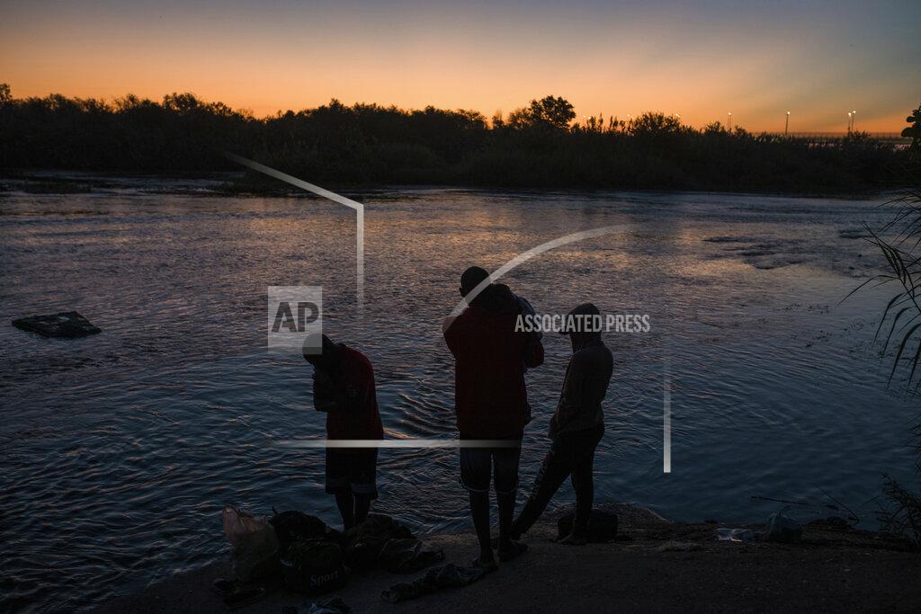 Felix Marquez A migrant family stands on the shore of the Rio Grande before crossing from Ciudad Acuña, Mexico, into Del Rio, Texas, at sunrise Sunday, Sept. 19, 2021. (AP Photo/Felix Marquez)