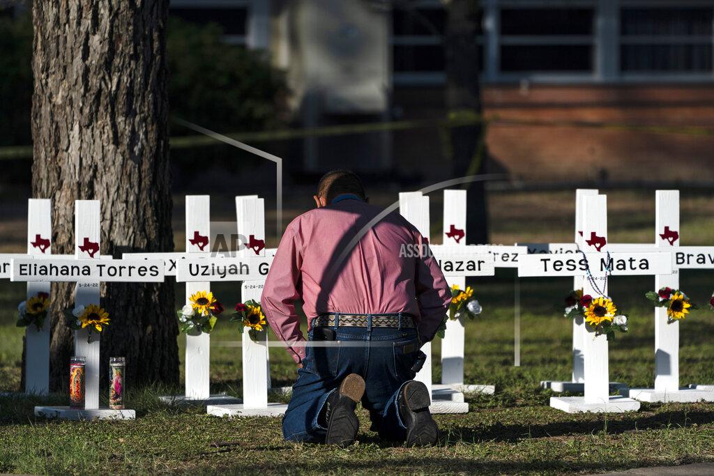 Jae C. Hong Pastor Daniel Myers kneels in front of crosses bearing the names of Tuesday's shooting victims while praying for them at Robb Elementary School in Uvalde, Texas, Thursday, May 26, 2022. (AP Photo/Jae C. Hong)