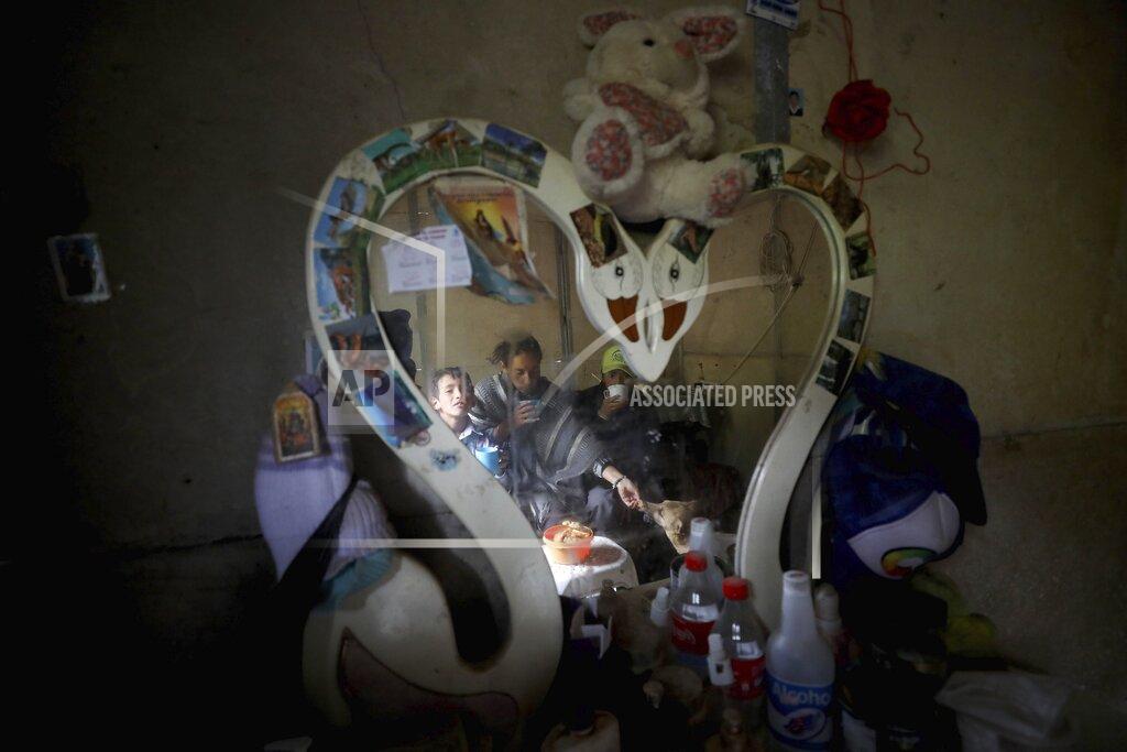 Fernando Vergara Nubia Rocio Gaona, 37, center, her sons, David, 14, right, and Jeimmer, 9, are reflected in a mirror during breakfast, at their home in Chipaque, Colombia, Saturday, May 9, 2020. The small-time farming mother and two sons are reinventing themselves as YouTubers due to a quarantine ordered by the government to contain the spread of COVID-19, teaching others how to grow vegetables at home and providing self-starter kits that they deliver through a local courier. (AP Photo/Fernando Vergara)