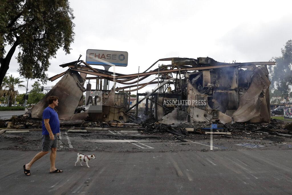 Gregory Bull A man passes a bank burned during a protest over the death of George Floyd, Sunday, May 31, 2020, in La Mesa, Calif. Protests were held in U.S. cities over the death of Floyd, a black man who died after being restrained by Minneapolis police officers on May 25. (AP Photo/Gregory Bull)