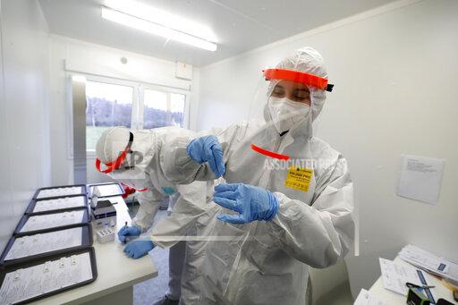 FILE- Medical workers examine the rapid antigen tests for the coronavirus in Prague, Czech Republic, Wednesday, Dec. 16, 2020. Czech Republic's Health Minister Vlastimil Valek said Friday Jan. 14, 2022 that the new Czech government will allow some people who have been tested positive for the coronavirus to keep working, an extraordinary measure to ease possible staff shortages caused by an anticipated surge of the omicron variant. The measure, which was used during the previous coronavirus waves, would only apply for workers at the health care system and in nursing homes who have no symptoms of COVID-19. (AP Photo/Petr David Josek, file)