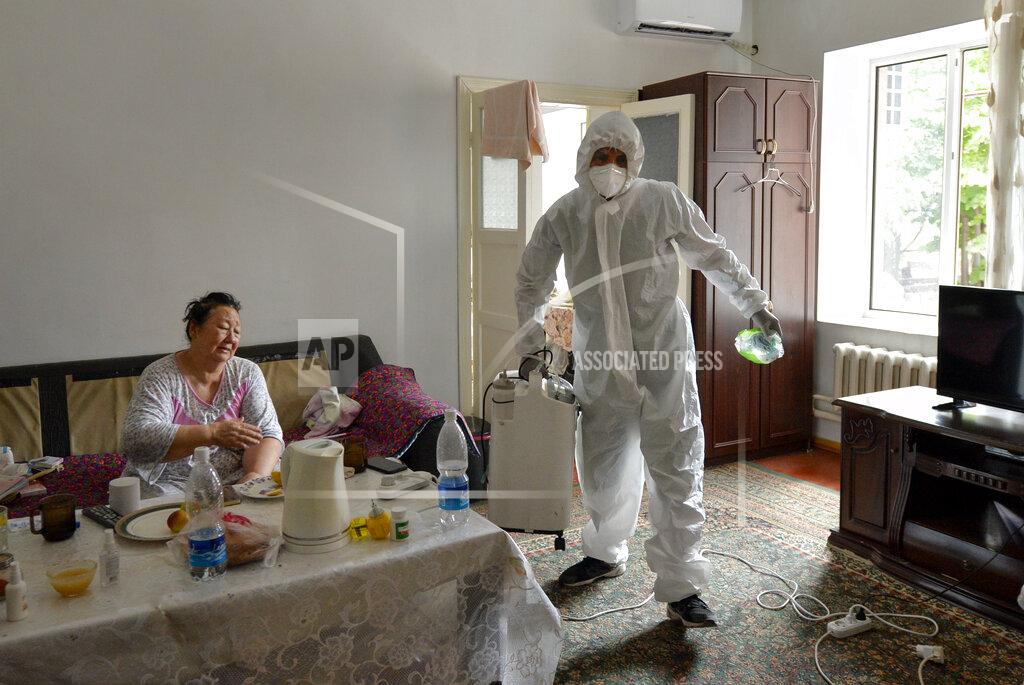 Vladimir Voronin A volunteer in protective suit and gloves carries an oxygen concentrator to help a suspected coronavirus patient breathe at her apartment in Bishkek, Kyrgyzstan, Friday, July 24, 2020. Volunteers have played a big role in dealing with a wave of coronavirus cases that has hit Kyrgyzstan. Many started doing house calls to patients who couldn't get into a hospital, bringing oxygen concentrators with them. (AP Photo/Vladimir Voronin)