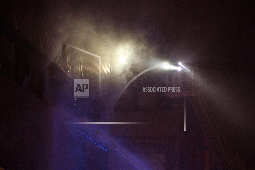 Joan Mateu Firefighters work to extinguish a fire at a building in Badalona, Barcelona, Spain, Thursday, Dec. 10, 2020. Authorities in northeastern Spain say a fire has raged through an abandoned building occupied by squatters in the city of Badalona, injuring at least 17 people, including two in critical condition. Firefighters say they rescued around 30 people from windows as the building burned late Wednesday. (AP Photo/Joan Mateu)