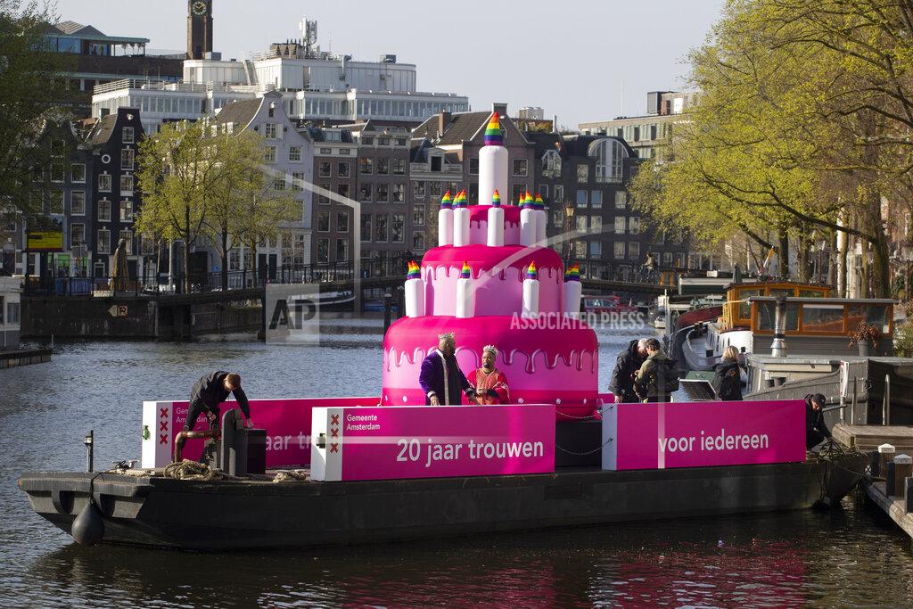Peter Dejong A huge inflatable pink cake with candles spouting rainbow flames glided through the Amsterdam canals Thursday as the Dutch capital celebrated the 20th anniversary of the world's first legal same-sex marriages, Thursday, April 1, 2021. Twenty years ago, the mayor of Amsterdam married four couples in City Hall as the Netherlands became the first country in the world with legalized same-sex marriage. It's now legal in 28 countries. (AP Photo/Peter Dejong)