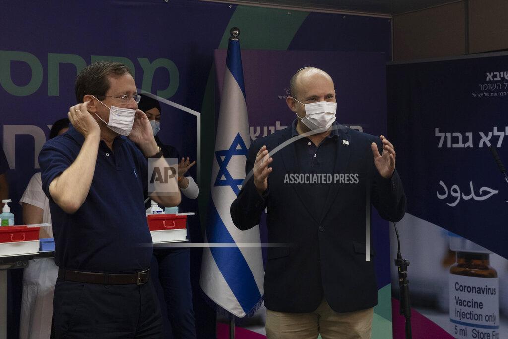 Maya Alleruzzo Israeli President Isaac Herzog left, puts on his mask as Prime Minister Naftali Bennett, right, speaks to journalists after Herzog received a third coronavirus vaccine at Sheba Medical Center in Ramat Gan, Israel, Friday, July 30, 2021. (AP Photo/Maya Alleruzzo, Pool)