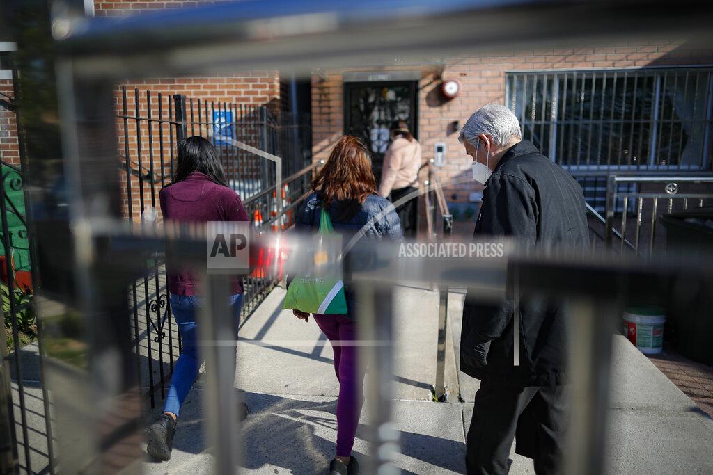John Minchillo Fabian Arias, a Lutheran pastor with Saint Peter's Church in Manhattan, right, is lead into a home to provide an in-home funeral service for Graciela Ruiz Martinez who died of COVID-19, Sunday, May 10, 2020, in the Queens borough of New York. (AP Photo/John Minchillo)