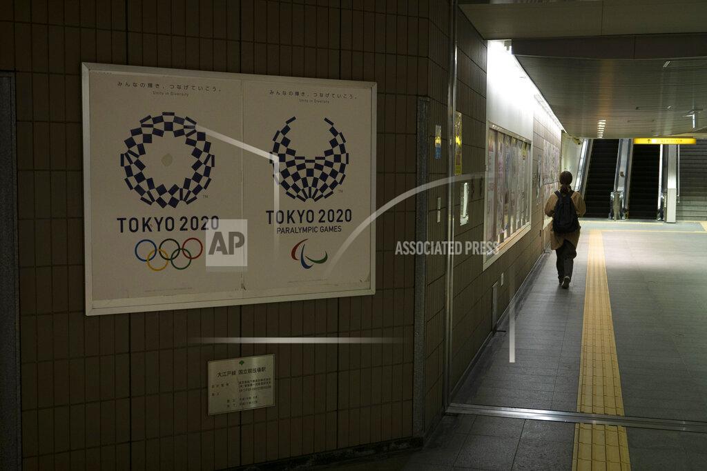 Jae C. Hong A commuter leaves a train station adorned with posters promoting the Tokyo 2020 Olympics in Tokyo, Monday, March 23, 2020. The IOC will take up to four weeks to consider postponing the Tokyo Olympics amid mounting criticism of its handling of the coronavirus crisis that now includes a call for delay from the leader of track and field, the biggest sport at the games. (AP Photo/Jae C. Hong)