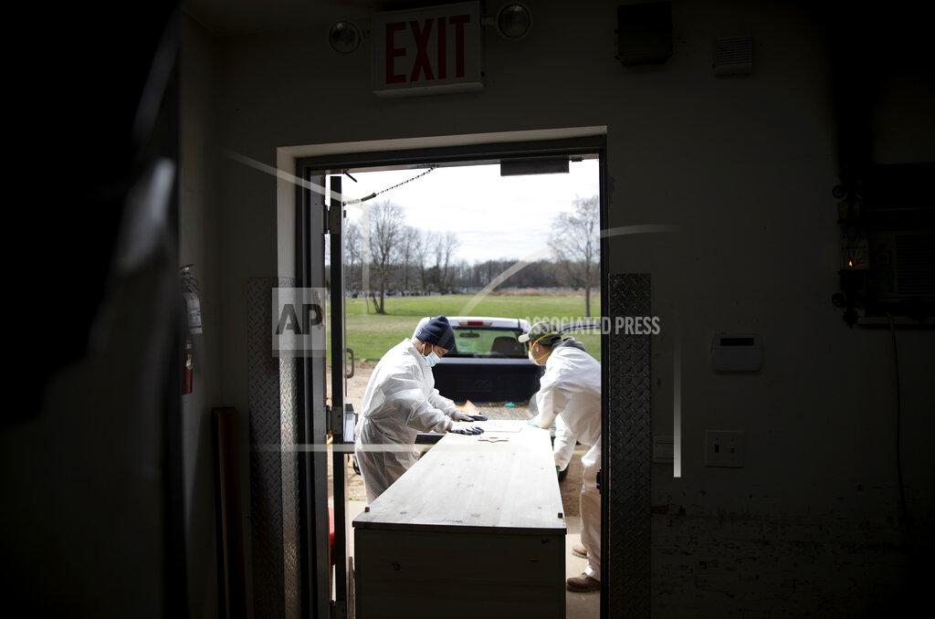 David Goldman Gravedigger Thomas Cortez, left, helps load a casket of someone who is presumed to have died from coronavirus as they keep pace with a surge in burials at Mount Richmond Cemetery in the Staten Island borough of New York, Tuesday, April 7, 2020. "It's sad, it's sad, and I feel sorry because they want to see. They can't. They have to be in the car and can't go and cry where it has to be," said Cortez of family members who must remain in their cars for burials and can't approach the grave. (AP Photo/David Goldman)