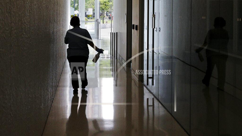 Charles Krupa FILE— In this July 23, 2020, file photo, a worker from Boston University's maintenance department carries a bottle of sanitizer, due to concerns over the COVID-19 virus outbreak, while making her cleaning rounds at a campus building in Boston. The university is urging students to stay on campus for Thanksgiving or, if they go home, stay away for the rest of the semester, joining a growing number of U.S. universities working to curb the spread of the coronavirus around the holidays. (AP Photo/Charles Krupa, File)