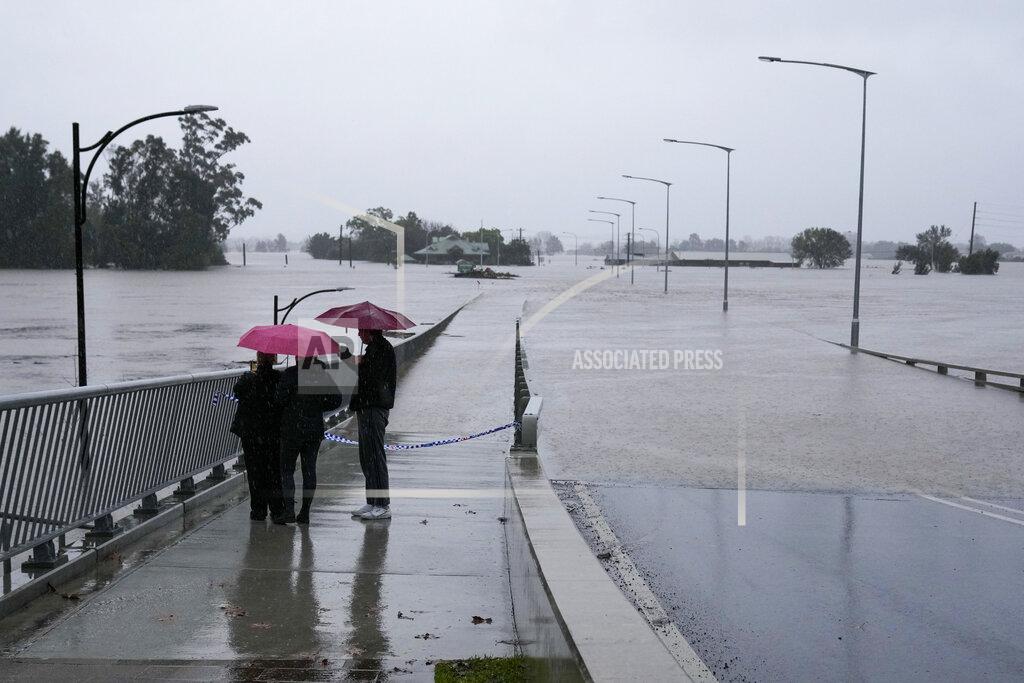 Mark Baker People look at the flooded Windsor Bridge on the outskirts of Sydney, Australia, Monday, July 4, 2022. More than 30,000 residents of Sydney and its surrounds have been told to evacuate or prepare to abandon their homes on Monday as Australia's largest city braces for what could be its worst flooding in 18 months. (AP Photo/Mark Baker)