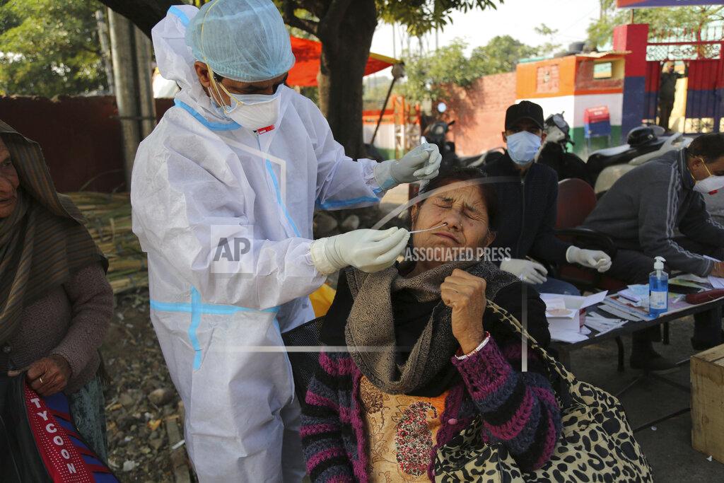 Channi Anand A health worker collects a swab sample from a woman to test for COVID-19 by a road side in Jammu, India, Monday, Nov.30, 2020. India is second behind the U.S. in total coronavirus cases. Its recovery rate is nearing 94%. (AP Photo/Channi Anand)