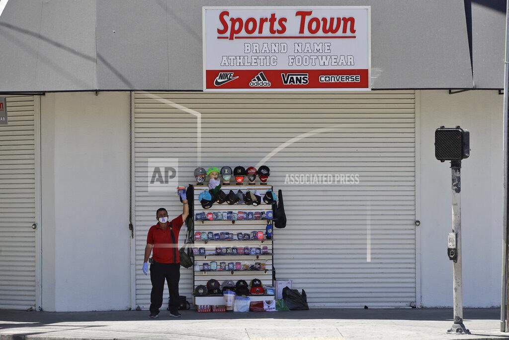 Marcio Jose Sanchez A man sells masks in front of a closed off sporting goods store Monday, May 4, 2020, in the fashion district of Los Angeles. Amid more defiance from local governments, California Gov. Gavin Newsom said Monday that some businesses can reopen as early as Friday with restrictions to help prevent spread of the coronavirus. The plan under the second phase of the governor's four-point reopening plan allows retailers such as clothing stores, sporting goods and florists to resume operations with curbside pickup. (AP Photo/Marcio Jose Sanchez)
