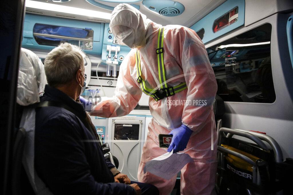 Luca Bruno Medical staffer Ruggero Gariboldi, right, treats a suspected Covid patient inside inside the ambulance during a shift with the emergency White Cross in Monza, Italy, Friday, Nov. 20, 2020. The city of Monza north of Milan is best known for its Formula 1 racetrack. In 2020, it has been the ambulance service that has been doing most of the racing. Over three days that an Associated Press photographer traveled on night calls with an ambulance service, the Monza-Brianza province of some 875,000 bordering Milan added 2,500 new cases, part of Italy’s new epicenter in the Lombardy region. (AP Photo/Luca Bruno)