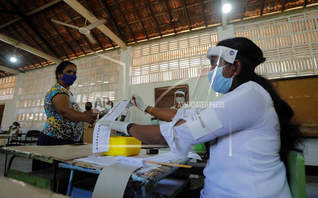 Eranga Jayawardena A Sri Lankan polling officer issues a ballot paper to a voter during a mock election ahead of the country's parliamentary poll in Negombo, Sri Lanka, Saturday, June 13, 2020. Sri Lanka's Election Commission set Aug. 5 as the new date for parliamentary elections after postponing them twice over the coronavirus pandemic. (AP Photo/Eranga Jayawardena)