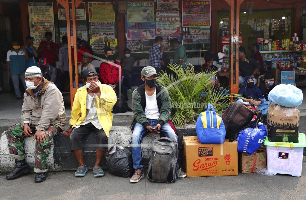 Tatan Syuflana People wait for a bus to take them to their home villages at the Kalideres bus terminal in Jakarta, Indonesia, Wednesday, May 5, 2021. The mass exodus out of major cities in the world's most populous Muslim country is underway despite travel restrictions imposed by the government to prevent the spread of coronavirus outbreak, as people are heading home to their villages to celebrate Eid al-Fitr holiday that marks the end of the holy fasting month of Ramadan on May 13. (AP Photo/Tatan Syuflana)