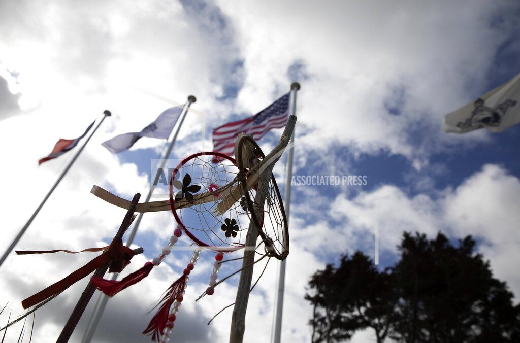 Virginia Mayo Native American dreamcatchers and an American flag wave in the wind prior to a ceremony at the Charles Shay World War II memorial at Omaha Beach in Saint-Laurent-sur-Mer, Normandy, France, Friday, June 5, 2020. Saturday's anniversary of D-Day will be one of the loneliest remembrances ever, as the coronavirus pandemic is keeping almost everyone away, from government leaders to frail veterans who might not get another chance for a final farewell to their unlucky comrades. Shay was a combat medic on D-Day, assigned to an assault battalion in the first wave of attacks on June 6, 1944. (AP Photo/Virginia Mayo)