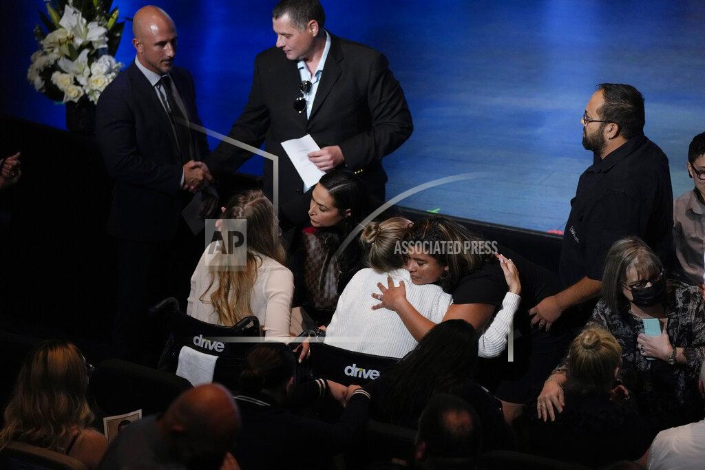Rebecca Blackwell Angela Gonzalez, center, and daughter Deven, left, both seated in wheelchairs due to their injuries, are embraced by well-wishers ahead of the funeral service for their late husband and father Edgar Gonzalez, 44, who was killed last month in the Champlain Towers South condominium collapse, on Friday, July 23, 2021, at Christ Fellowship church in Palmetto Bay, Fla. Angela and Deven were injured but survived the collapse, falling multiple stories. (AP Photo/Rebecca Blackwell)