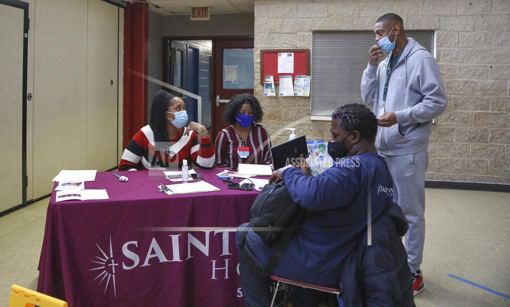 Teresa Crawford Community educator Asha Brown, left, tries to persuade Leo Baylor, standing right, to be vaccinated against COVID-19, in Chicago on Tuesday, Feb. 23, 2021. Brown, a respiratory therapist, was enlisted by Saint Anthony Hospital to promote vaccination in hard hit Black and brown neighborhoods. Baylor expressed reluctance but wanted more information. (AP Photo/Teresa Crawford)